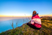 Woman sitting on a cliff looking out to sea, Gabicce Monte, Pesaro and Urbino, Italy — Foto stock