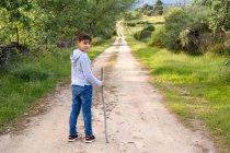 Хлопчик стоїть на стежці, тримаючи палицю, Іспанія. — стокове фото