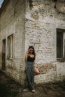 Молода стильна жінка в сонцезахисних окулярах позує на стару будівельну стіну — стокове фото