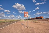 Train driving past a Historic Route 66 sign near Seligman, Arizona, United States — Stock Photo