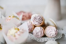Cupcakes, conos de gofre con crema batida y macarrones con decoraciones doradas - foto de stock