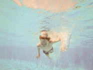 Menino nadando debaixo d 'água em uma piscina — Fotografia de Stock