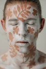 Портрет молодого чоловіка з білим обличчям та мистецтвом тіла з квітами — стокове фото