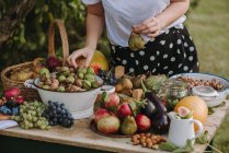 Обрізаний знімок жінки за столом зі свіжими фруктами та овочами — стокове фото