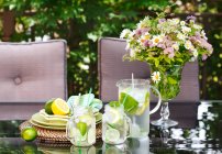 Лимонад в глечику і чашки на столі в саду . — стокове фото