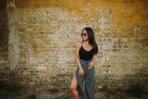 Stylische asiatische junge Frau steht vor alter Backsteinmauer — Stockfoto