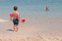 Pai e filho brincando com uma bola de praia no oceano, Grécia — Fotografia de Stock