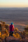 Woman standing on Mt Sonder taking a photo at sunrise, West MacDonnell National Park, Northern Territory, Australia — Foto stock