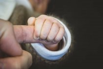 Primer plano de un bebé sosteniendo el dedo de un padre - foto de stock
