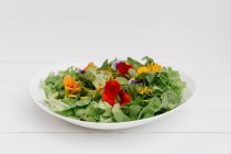Placa de ensalada verde con flores comestibles - foto de stock
