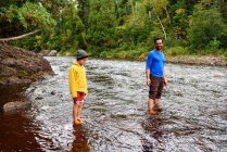 Padre e hijo de pie en un río, Estados Unidos - foto de stock