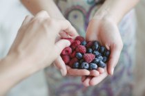 Woman sharing blueberries and raspberries with a friend — Stock Photo