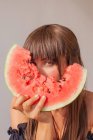 Frau versteckt sich hinter einer Scheibe Wassermelone — Stockfoto