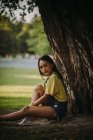 Donna sorridente seduta sotto un albero nel parco, Serbia — Foto stock