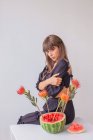 Femme debout par un arrangement de fleurs de protéa dans une pastèque — Photo de stock