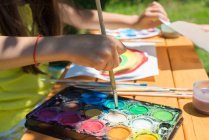 Menina sentada no jardim pintura com tinta aquarela — Fotografia de Stock