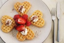 Waffles em forma de coração com morangos frescos e creme — Fotografia de Stock
