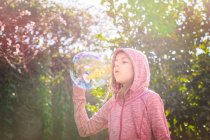 Boy standing in garden and blowing soap bubbles — Stock Photo
