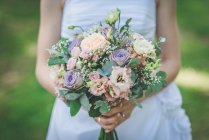 Primo piano di una sposa che tiene un mazzo di fiori — Foto stock