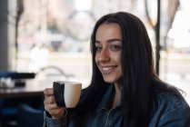 Retrato de una mujer sonriente bebiendo una taza de té - foto de stock