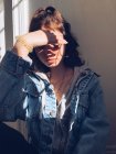 Retrato de adolescente cubriendo la cara con la mano en la luz del sol - foto de stock