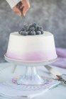 Woman serving a slice of Angel cake with cream and blueberries — Stock Photo