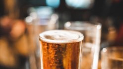 Gros plan d'une pinte de bière et de verres vides sur une table — Photo de stock