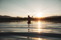 Silhouette eines Mannes, der in einem Fluss beim Fliegenfischen steht, USA — Stockfoto
