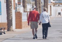 Coppia di anziani che cammina lungo una passeggiata sulla spiaggia, Malaga, Spagna — Foto stock
