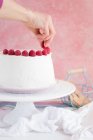 Torta crema di lamponi decorare mano femminile sul supporto torta, vista da vicino — Foto stock