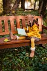 Mädchen mit Fliegermütze und Brille sitzt auf einer Bank und liest ein Buch, Bulgarien — Stockfoto
