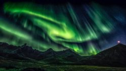 Green aurora borealis light over mountainous landscape — Stock Photo