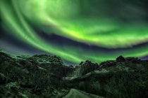Green aurora borealis light over mountainous landscape — Stock Photo