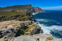 Picturesque view of rocky coast and wavy sea at sunny day — стоковое фото