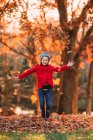 Девочка, бросающая осенние листья в воздух, США — стоковое фото