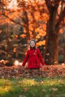 Chica sonriente lanzando hojas de otoño en el aire, Estados Unidos - foto de stock