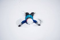 Garçon couché dans la neige faisant un ange de neige, Wisconsin, États-Unis — Photo de stock