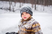Porträt eines schneebedeckten Jungen in winterlicher Park-Szene — Stockfoto