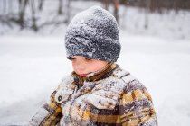 Portrait of boy child covered in snow in winter park scene — Stock Photo