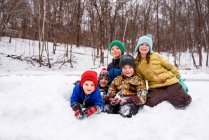 Cinque bambini felici sulla neve nella scena della foresta invernale — Foto stock