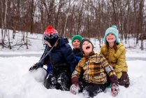 Quatro crianças felizes na neve na cena da floresta de inverno — Fotografia de Stock