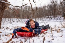 Ragazzo sdraiato su una slitta, Wisconsin, Stati Uniti — Foto stock