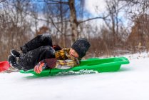 Boy sledging in the snow, Wisconsin, Estados Unidos - foto de stock