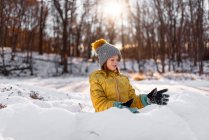 Retrato de una niña sonriente construyendo un fuerte de nieve, Estados Unidos - foto de stock