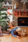 Garçon étreinte avec chien à Noël intérieur décoré — Photo de stock