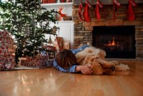 Ragazzo che abbraccia con cane in interni decorati di Natale — Foto stock