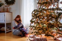 Mère et fils câlins par arbre de Noël à la maison — Photo de stock