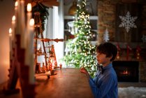 Niño de pie frente a un aparador mirando las decoraciones de Navidad - foto de stock