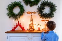 Garçon debout devant un buffet regardant les décorations de Noël — Photo de stock