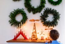 Мальчик стоит перед буфетом и смотрит на рождественские украшения. — стоковое фото